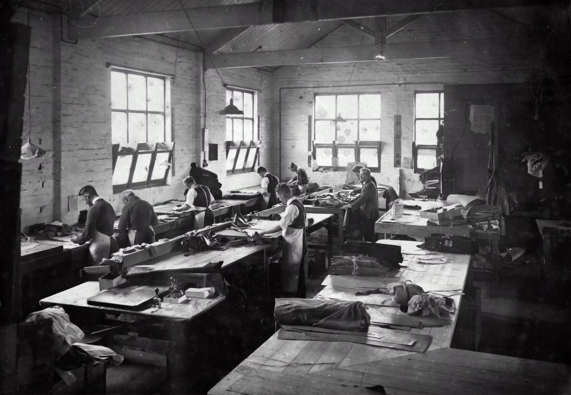 Workers at long wooden benches in the Simpson's Gloves factory, Richmond, around 1930